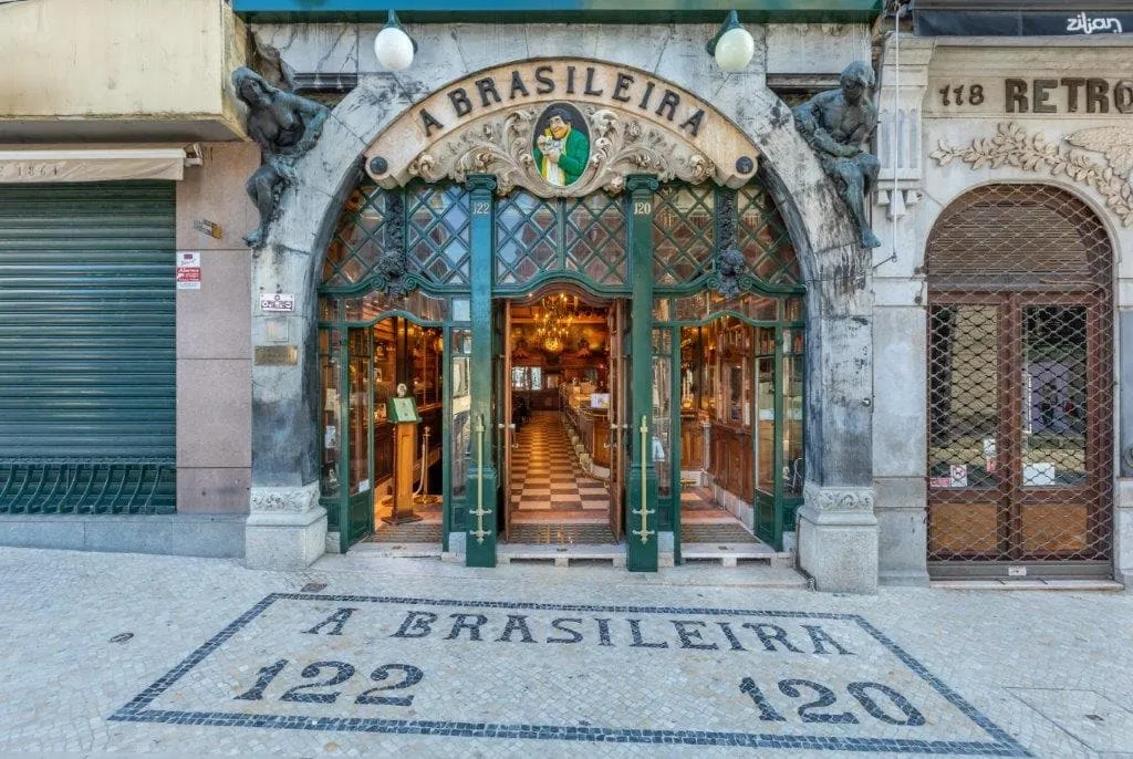 The green and gold entrance of the Café A Brasileira on Rua Garrett, with its name picked out in black and white stone on the pavement