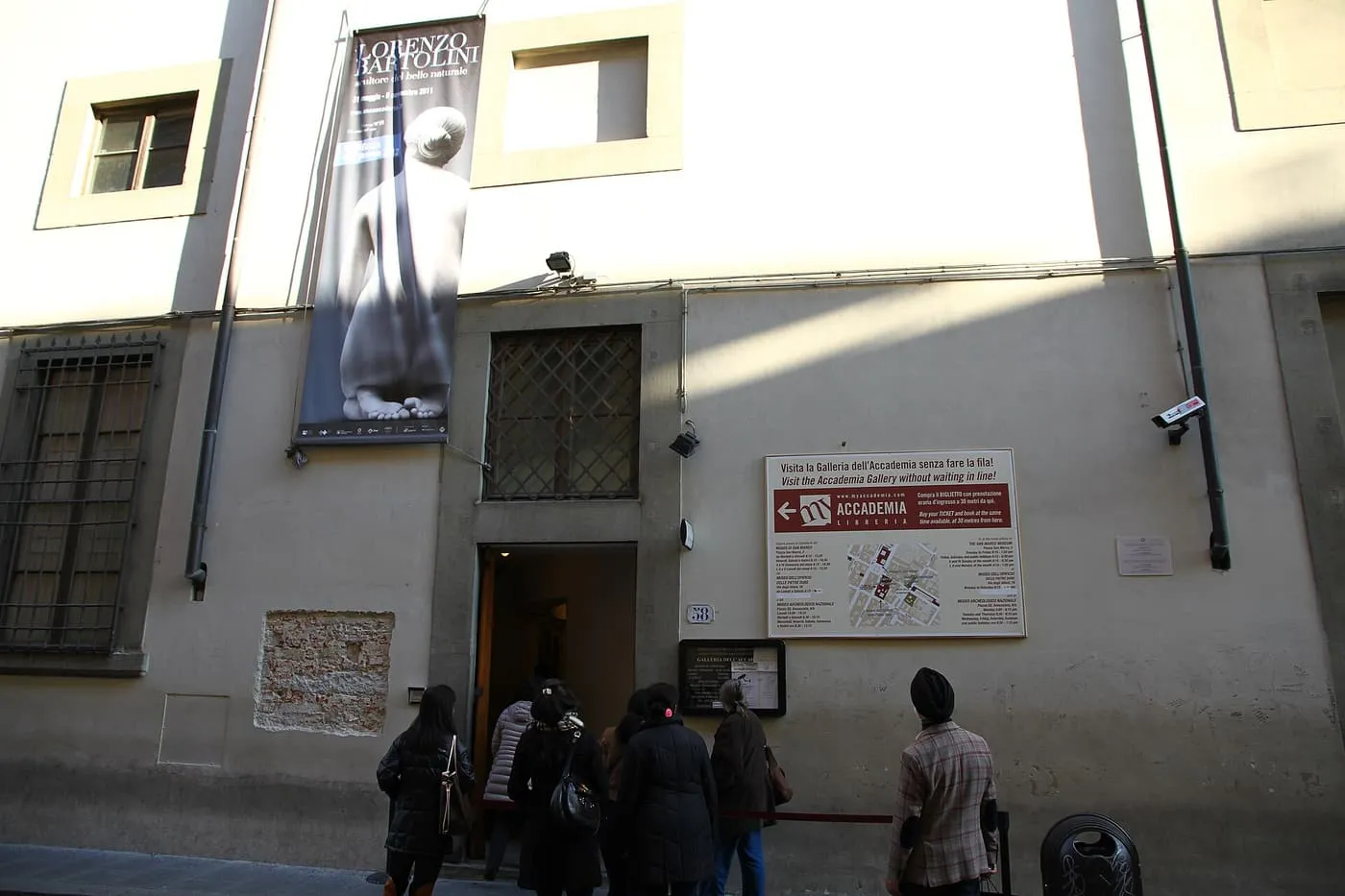 Visitors queuing at the doorway of the Galleria dell'Accademia on Via Ricasoli, under an exhibition banner
