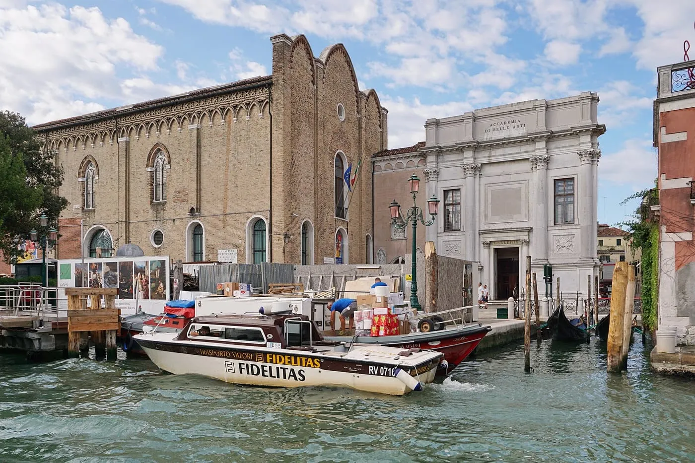 The white entrance of the Gallerie dell'Accademia beside the brick former church of Santa Maria della Carità, seen from the Grand Canal
