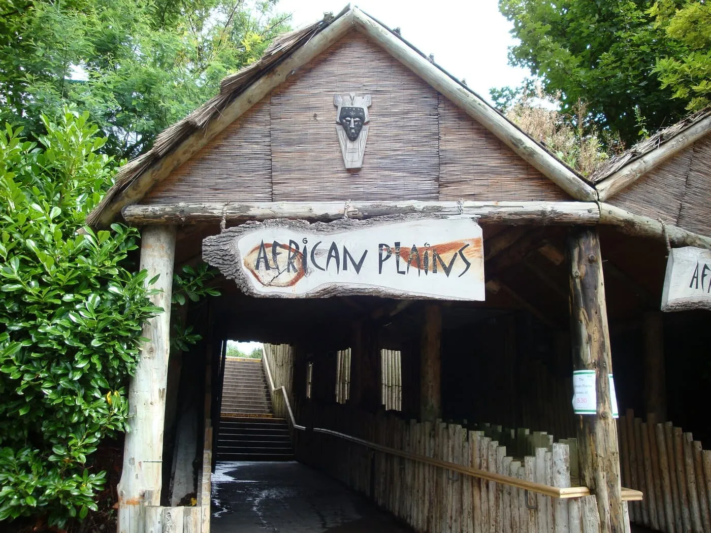 A timber-framed thatched gateway with an African Plains sign over a path and steps at Dublin Zoo