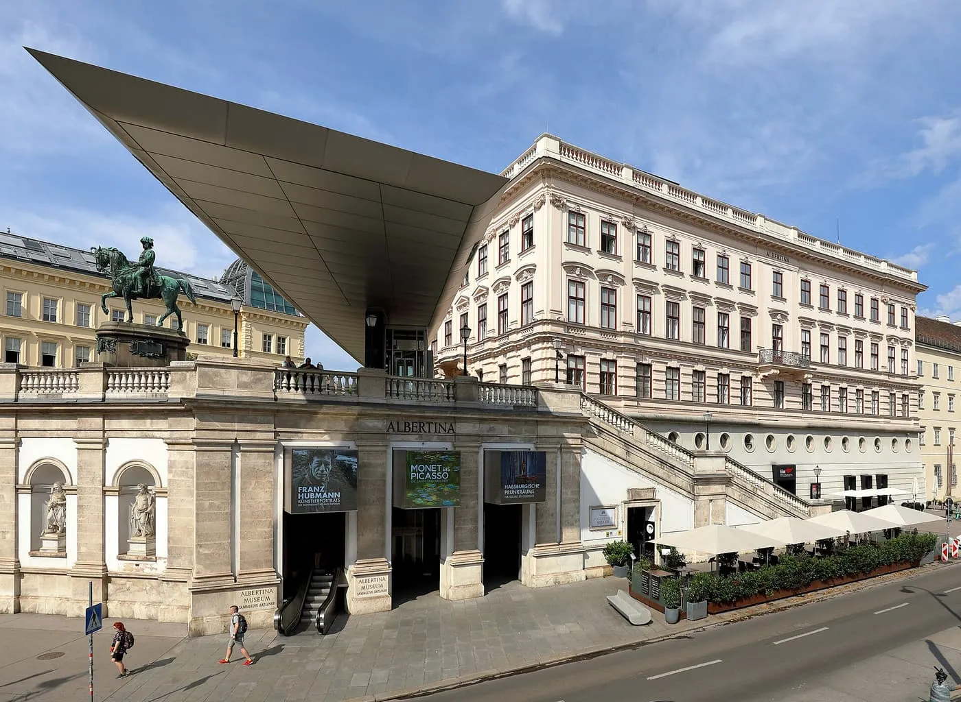 The Albertina on its bastion above the street, with a long cantilevered metal canopy over the entrance and café umbrellas on the terrace
