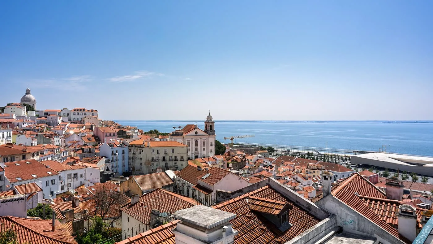 Terracotta rooftops of Alfama running down to the Tagus, with the dome of the National Pantheon at left