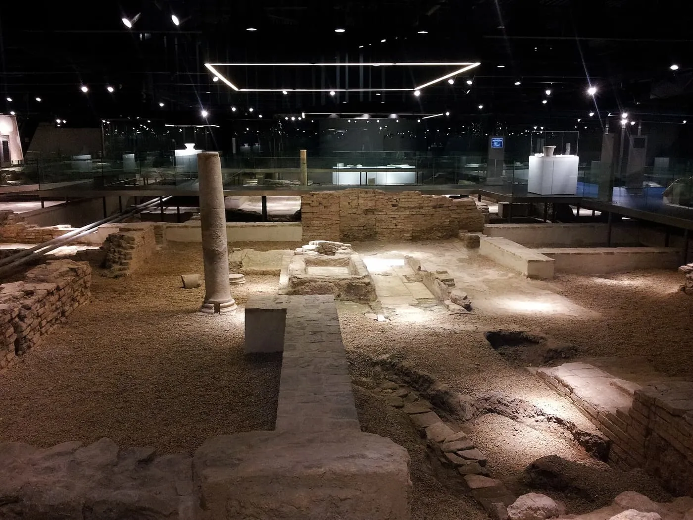 Roman and Islamic ruins lit from above in the Antiquarium, with a single column standing among low walls