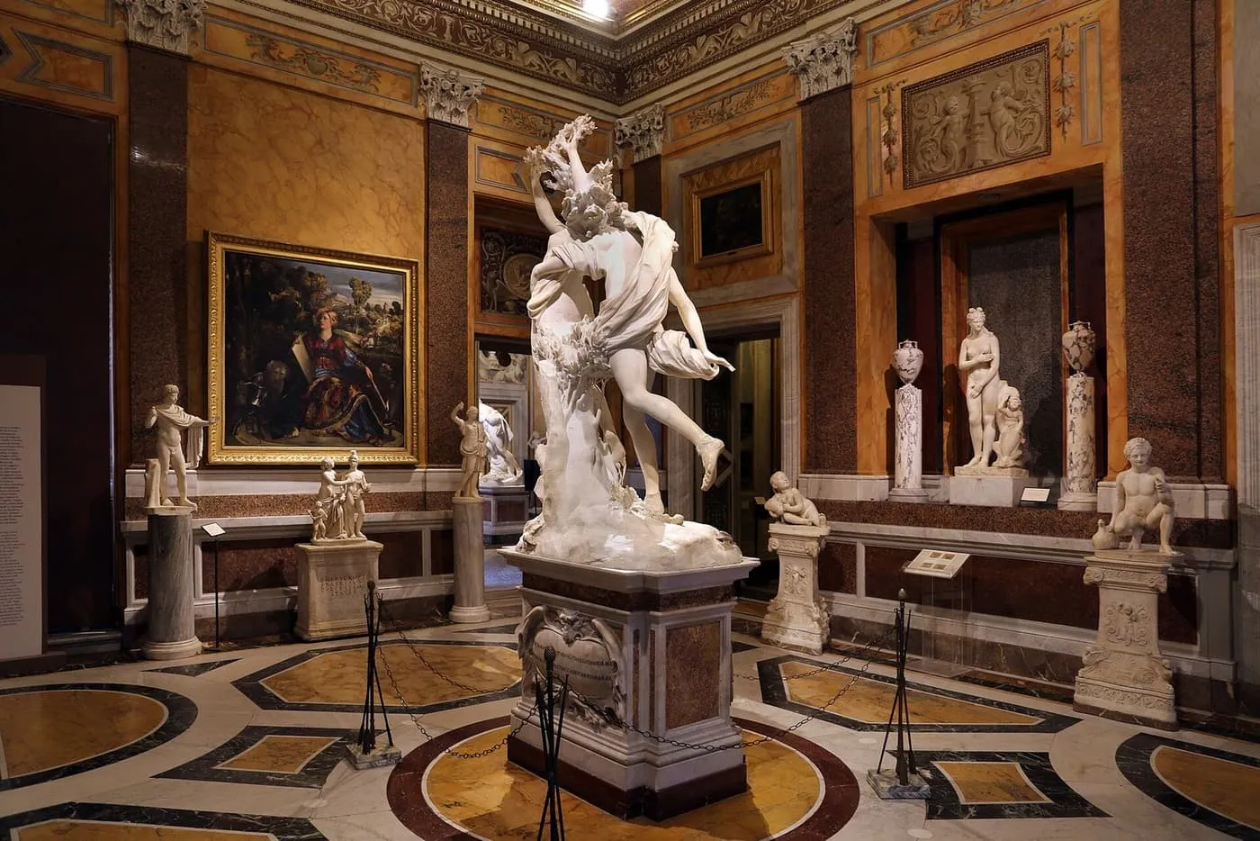 Bernini's marble Apollo and Daphne on a plinth in its room, with a painting, statues and a patterned marble floor around it