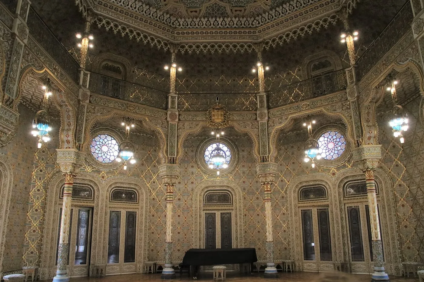 The octagonal Arabian Room of the Palácio da Bolsa, with gilded Moorish plasterwork, rose windows, blue-glass lamps and a grand piano