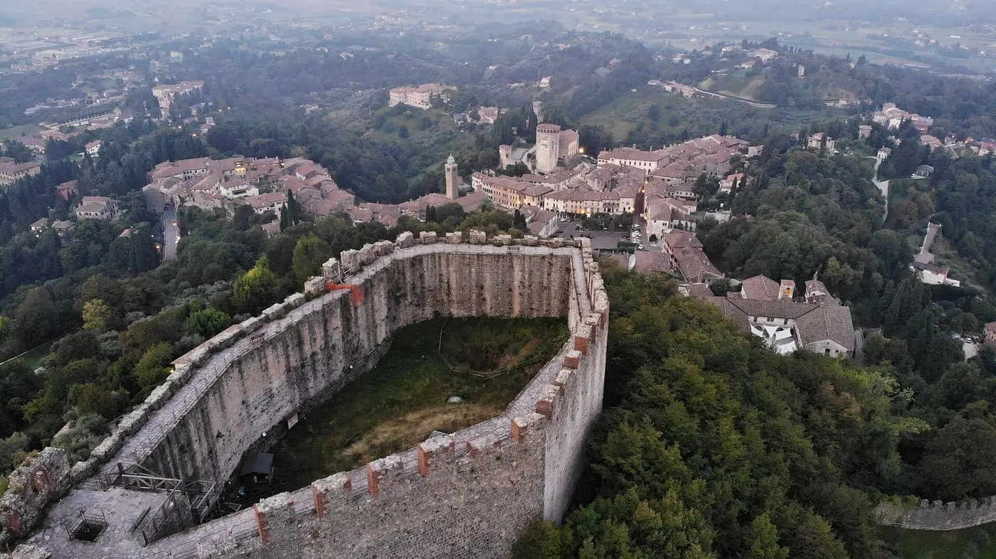 The walls of the Rocca fortress above Asolo, with the town's rooftops and a bell tower below