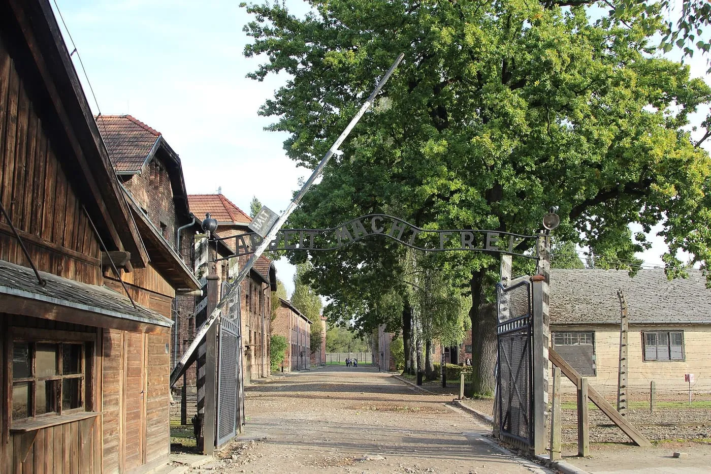 The gate at Auschwitz I with its overhead lettering, and the camp's buildings along the road beyond