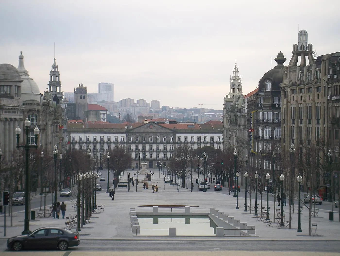 Avenida dos Aliados from its top end: a long avenue of lamp posts and bare trees, a rectangular pool in the foreground and a palace-like building at the far end