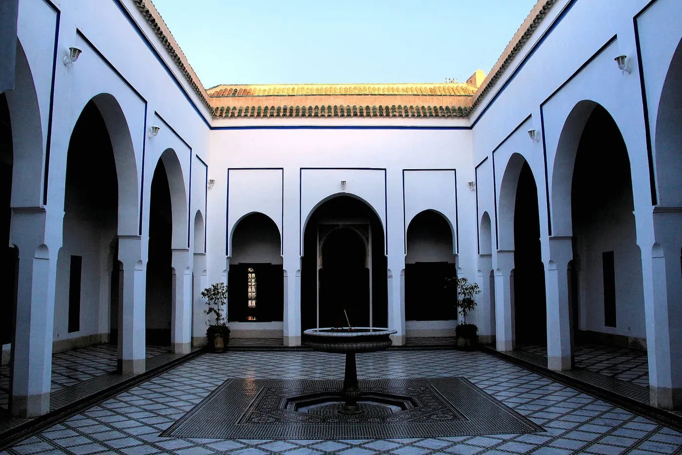 A white arcaded courtyard in the Bahia Palace, with a central fountain on a black and white tiled floor