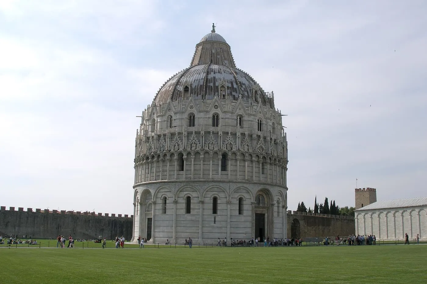 The round, domed Baptistery of Pisa standing on the lawn inside the square's walls
