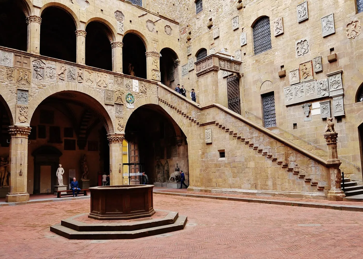 The courtyard of the Bargello, with a well, an outdoor staircase and arcades covered in carved coats of arms