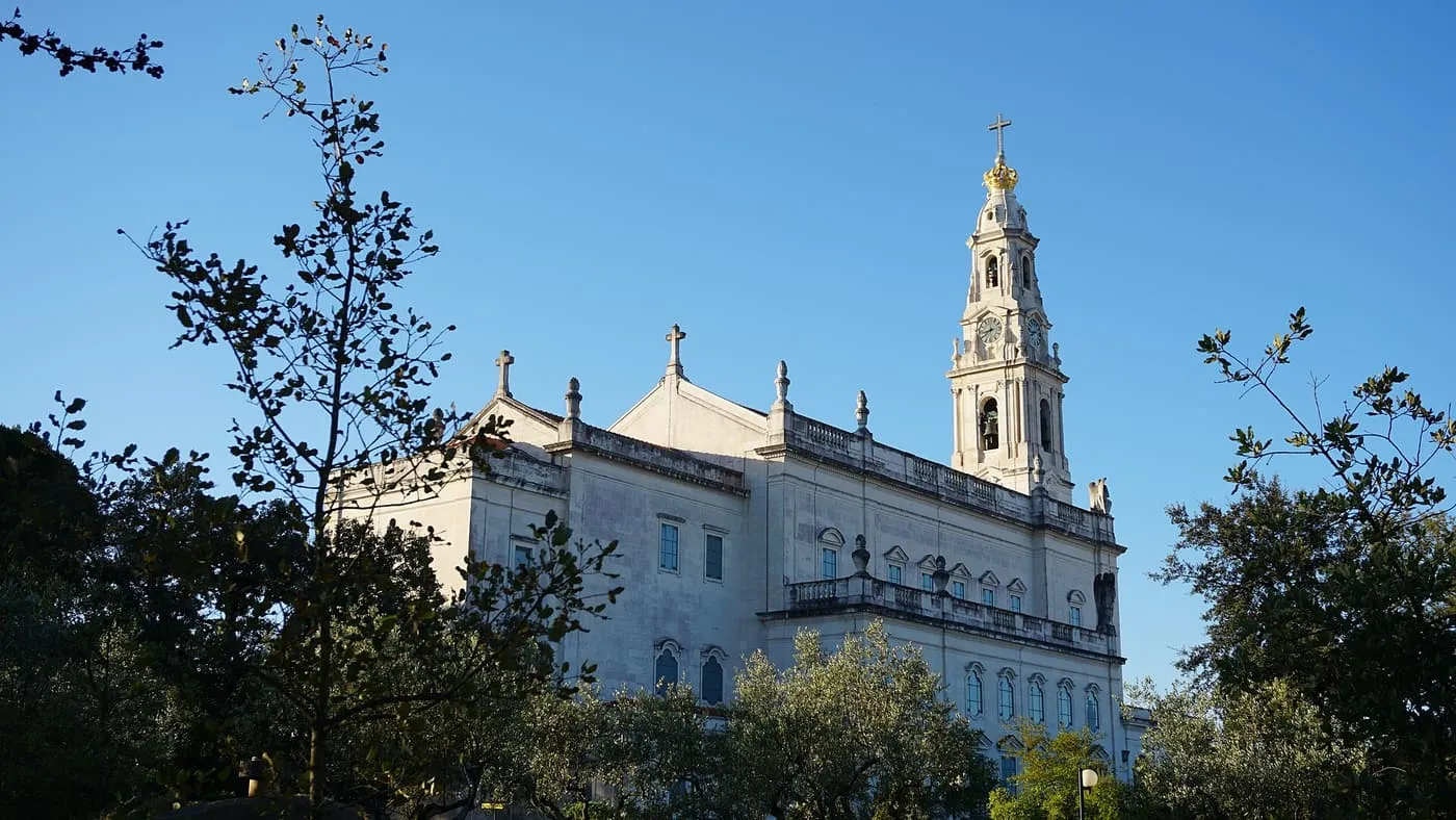 The white Basilica of Our Lady of the Rosary and its tower, seen from the trees at the side