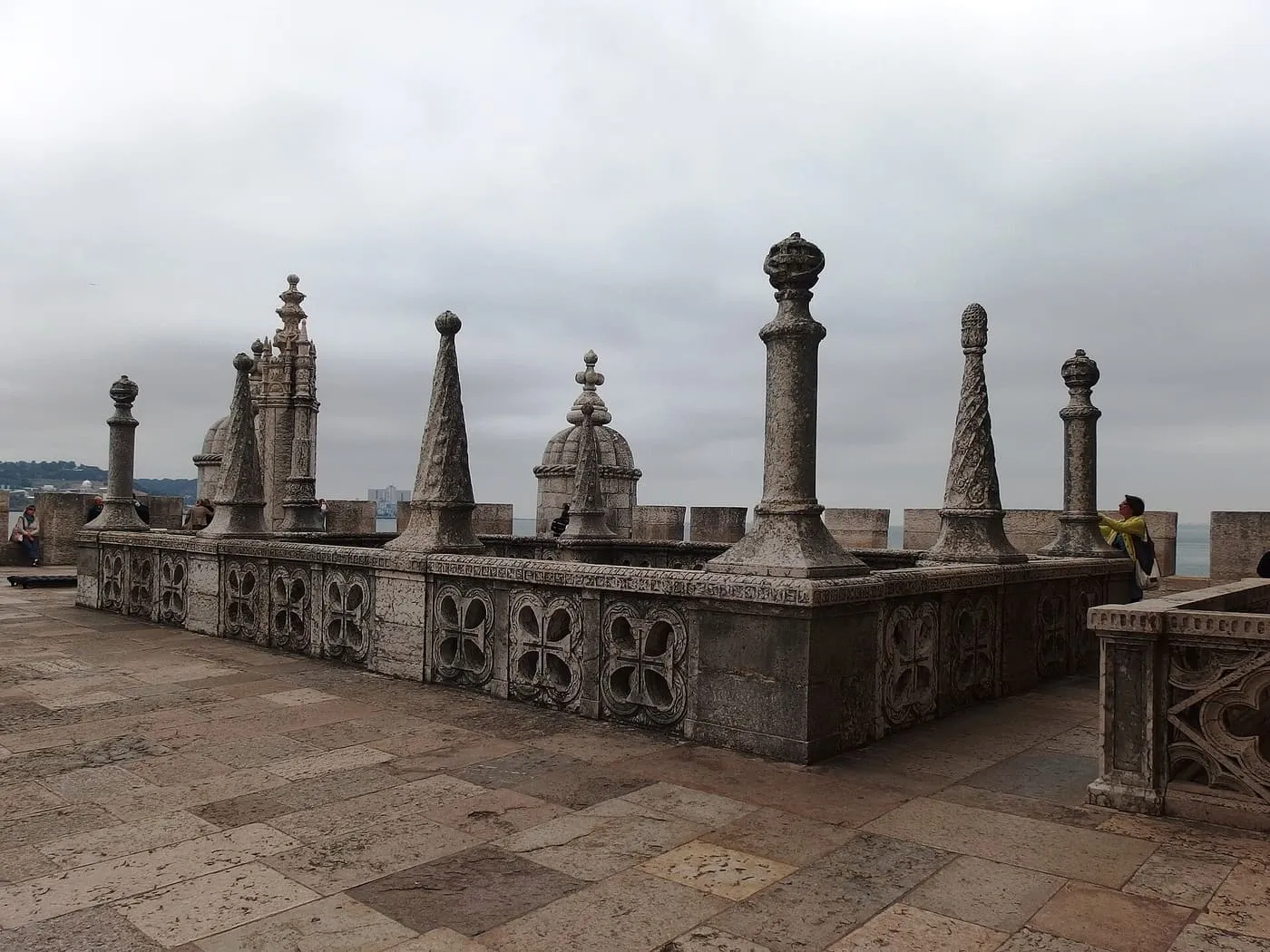 Stone finials and carved panels along the terrace on top of Belém Tower's bastion, under a grey sky