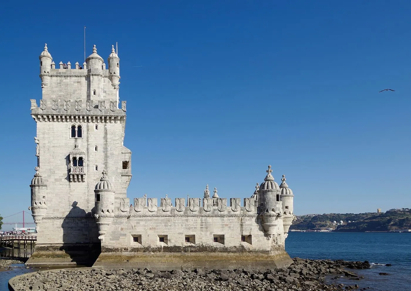 Belém Tower seen from the river bank, with the Ponte 25 de Abril in the distance