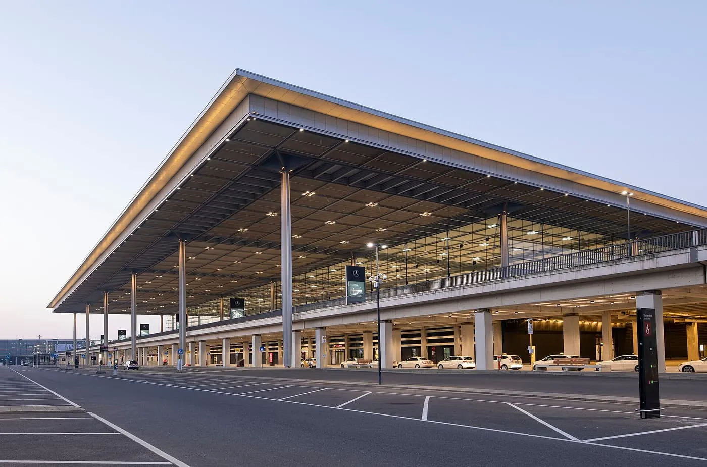 The long flat roof and glass front of Terminal 1 at Berlin Brandenburg Airport, with taxis waiting beneath the building