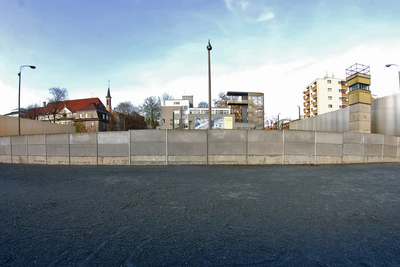 A section of the Wall on the Bernauer Straße memorial grounds, with a border watchtower and the Documentation Centre's viewing tower behind it