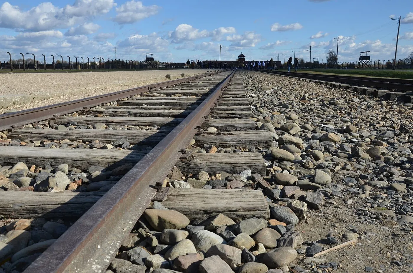 A railway line with stones between the sleepers, running towards the gatehouse at Auschwitz II-Birkenau