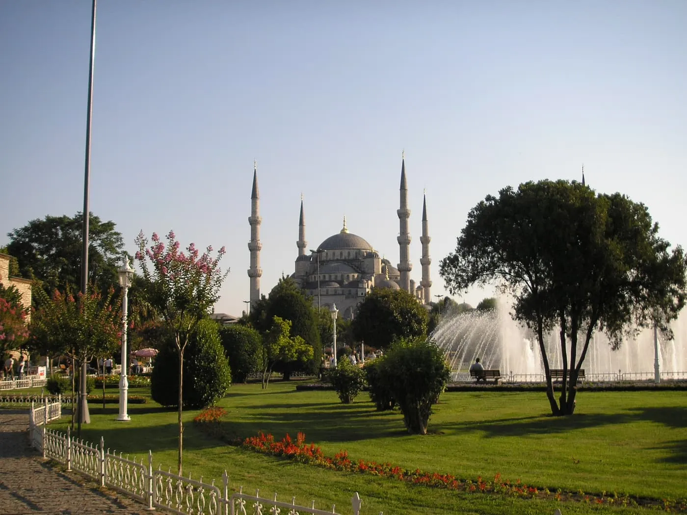 The Blue Mosque's domes and minarets across a lawn and a fountain in the park