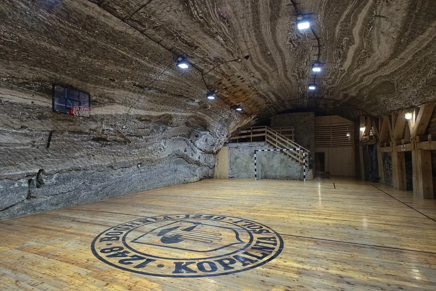 A long chamber with banded salt walls and a wooden sports floor in the Bochnia Salt Mine