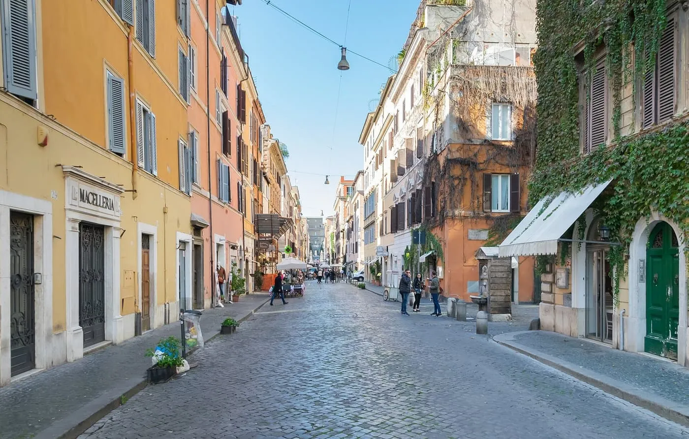 A cobbled street in Borgo Pio with shuttered houses in ochre and orange and ivy on the right