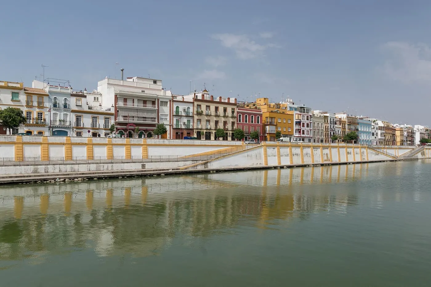 The coloured houses of Calle Betis above a white and yellow embankment wall on the Triana bank of the river