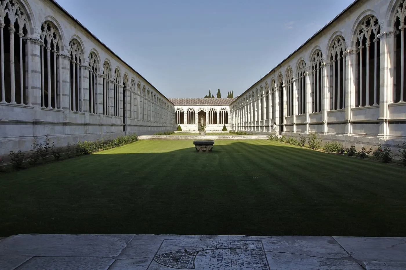 The long white arcaded cloister of the Camposanto around a lawn