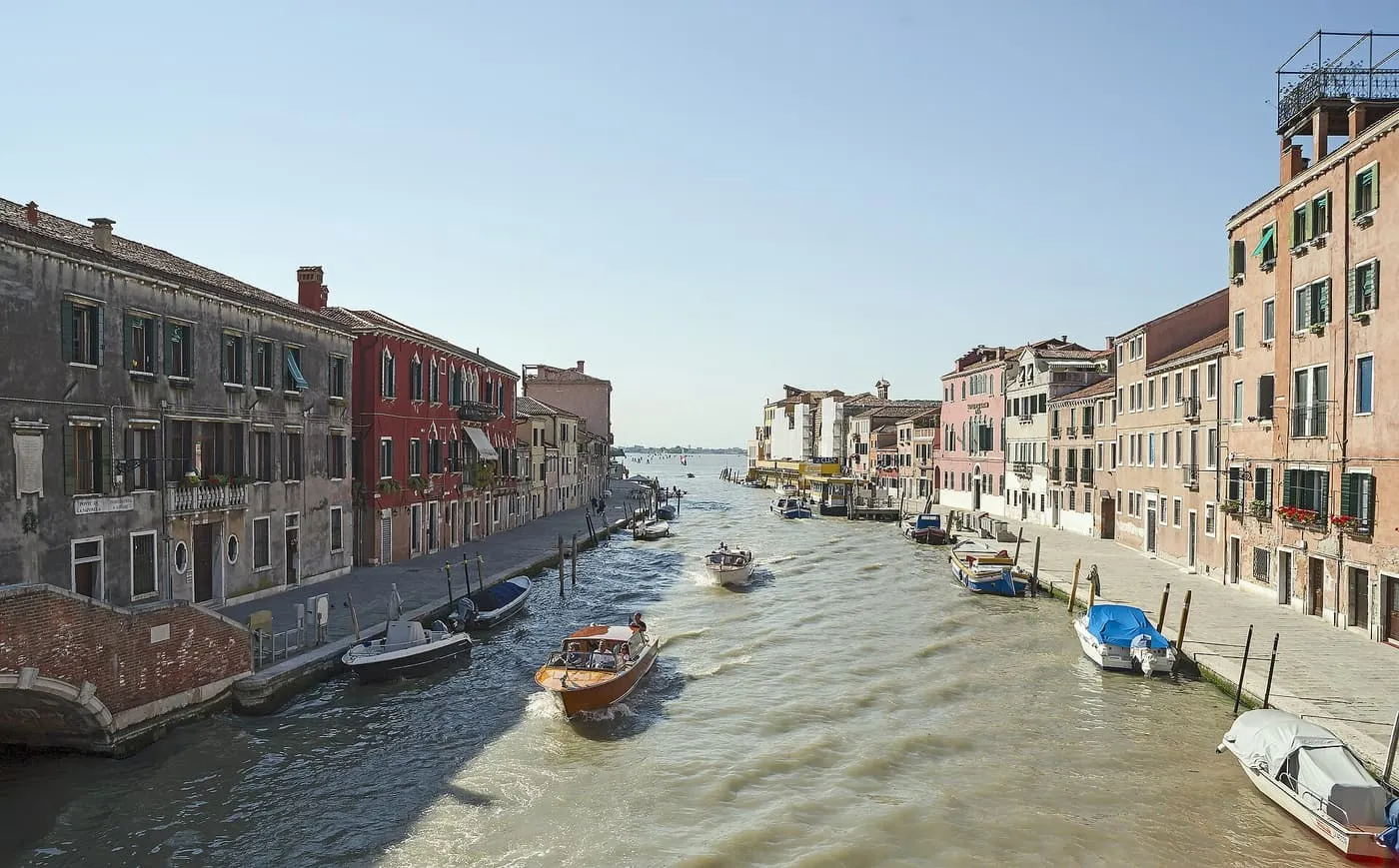 The wide Canale di Cannaregio with water taxis and moored boats, running towards the lagoon between brick and plaster houses