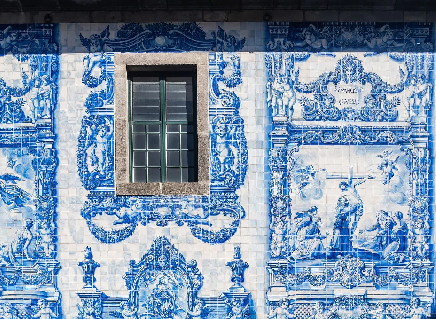 Blue-and-white azulejo panels framing a window on the wall of the Capela das Almas, with a scene of St Francis of Assisi