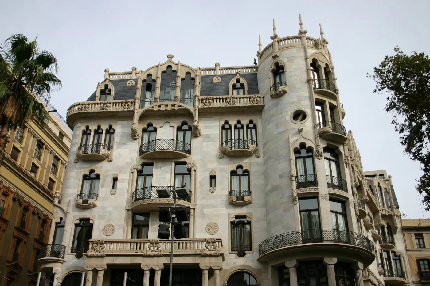 Casa Fuster on its corner, a pale stone building with a round tower, tall arched windows, balconies and a low gabled roof