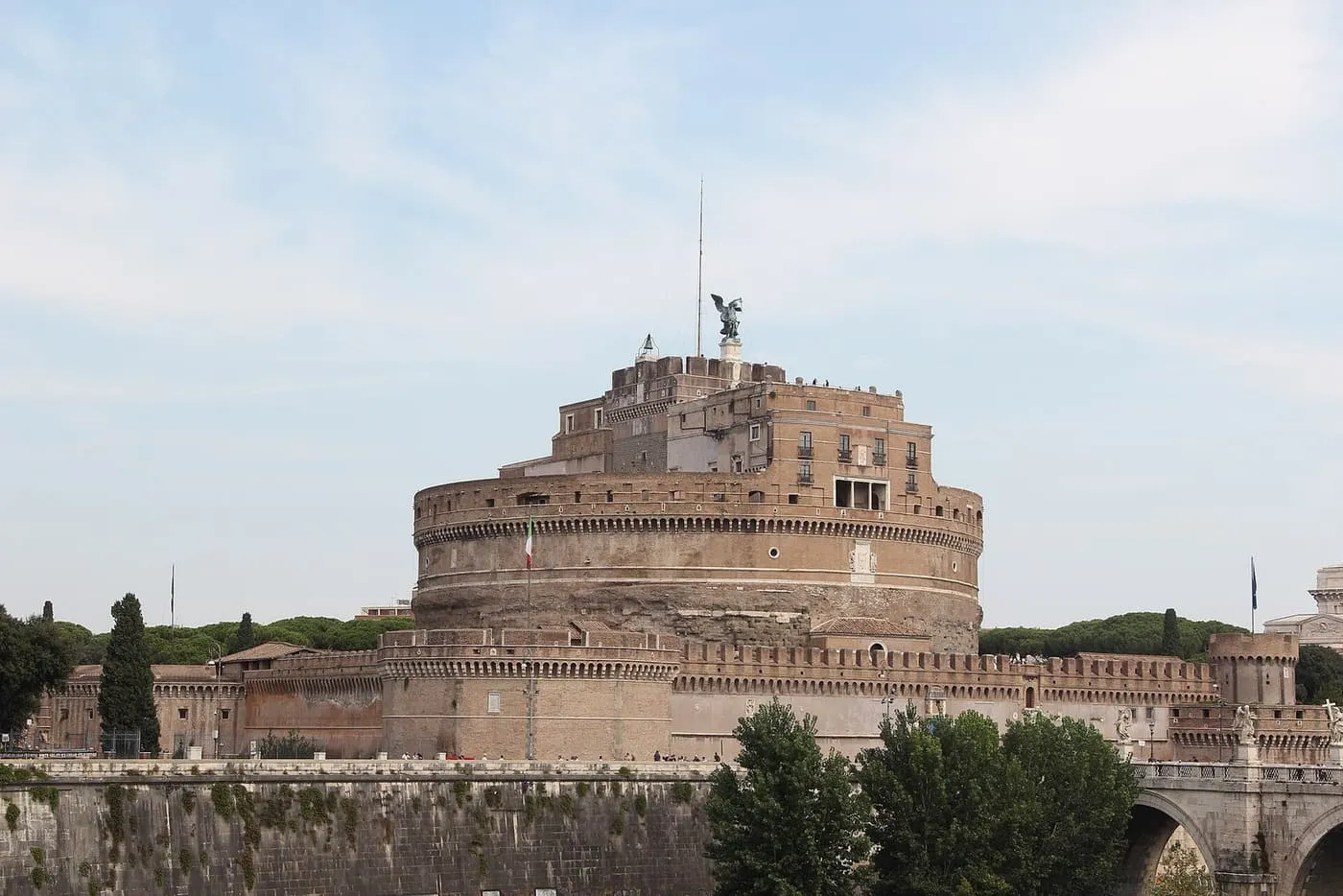 The round drum of Castel Sant'Angelo above the Tiber embankment, with the bronze angel on top and the bridge at the right