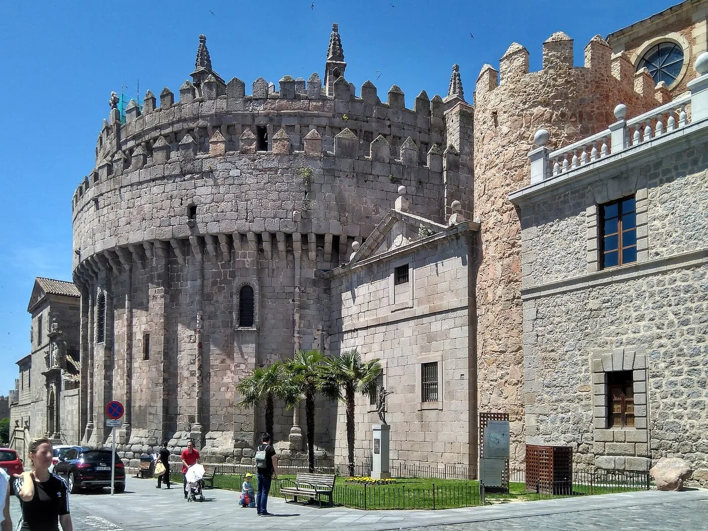 The battlemented apse of Ávila Cathedral, a round stone drum built into the line of the city wall beside a wall tower