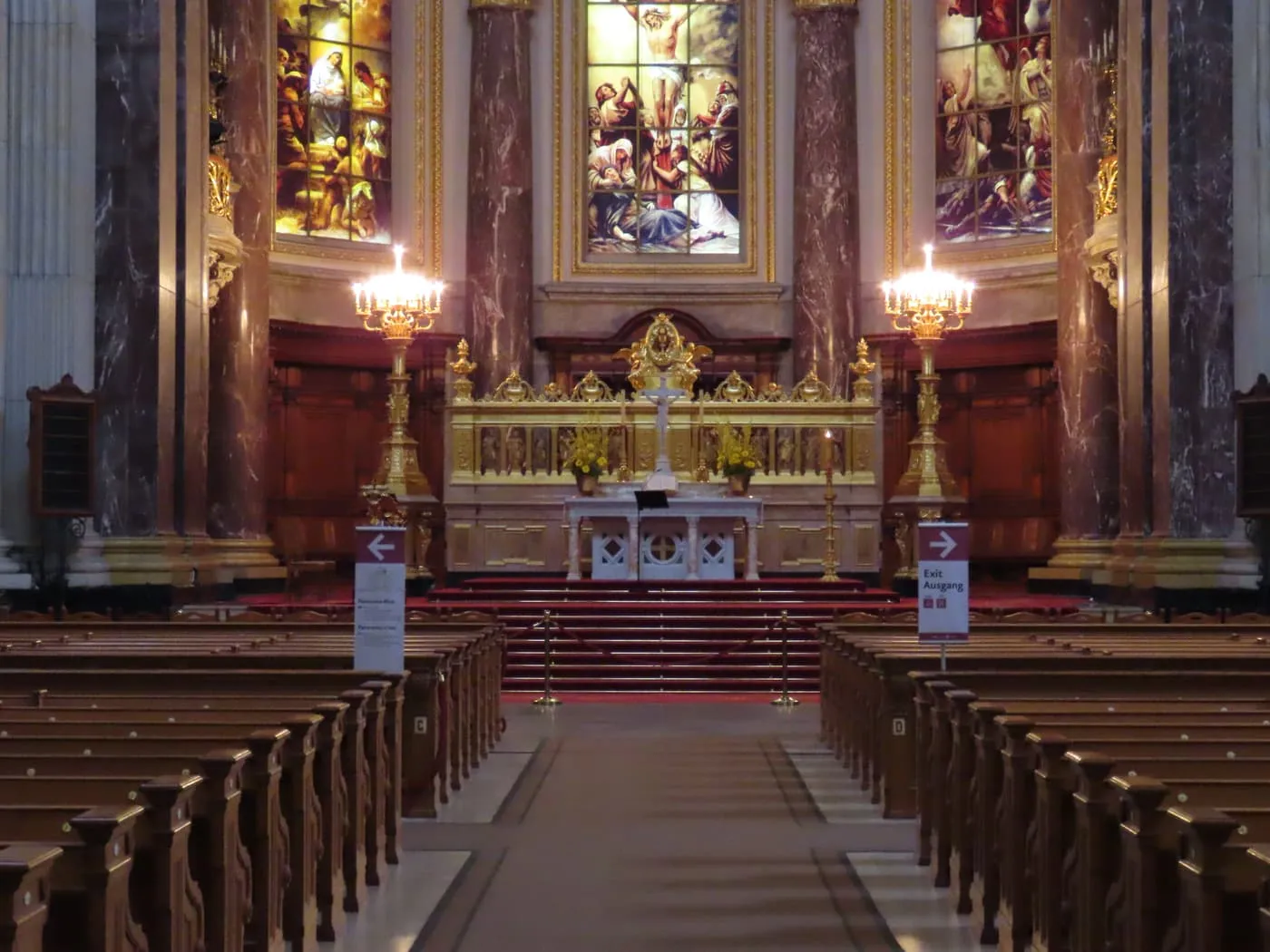 The altar of the Berlin Cathedral at the end of the nave, with rows of wooden pews and stained-glass windows above