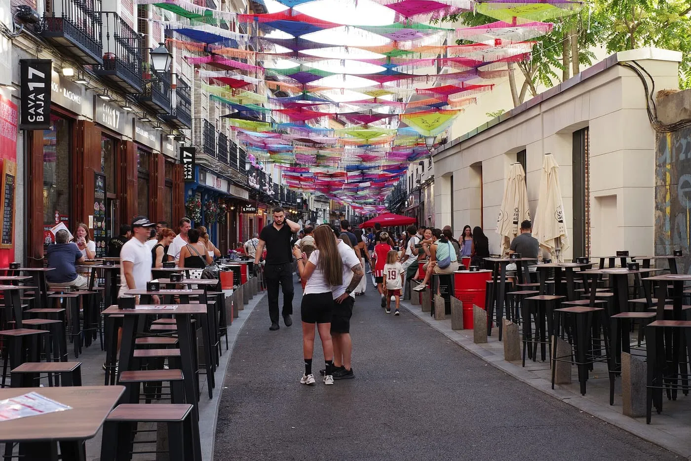 Calle de la Cava Baja with bar terraces on both sides and coloured cloths hung across the street