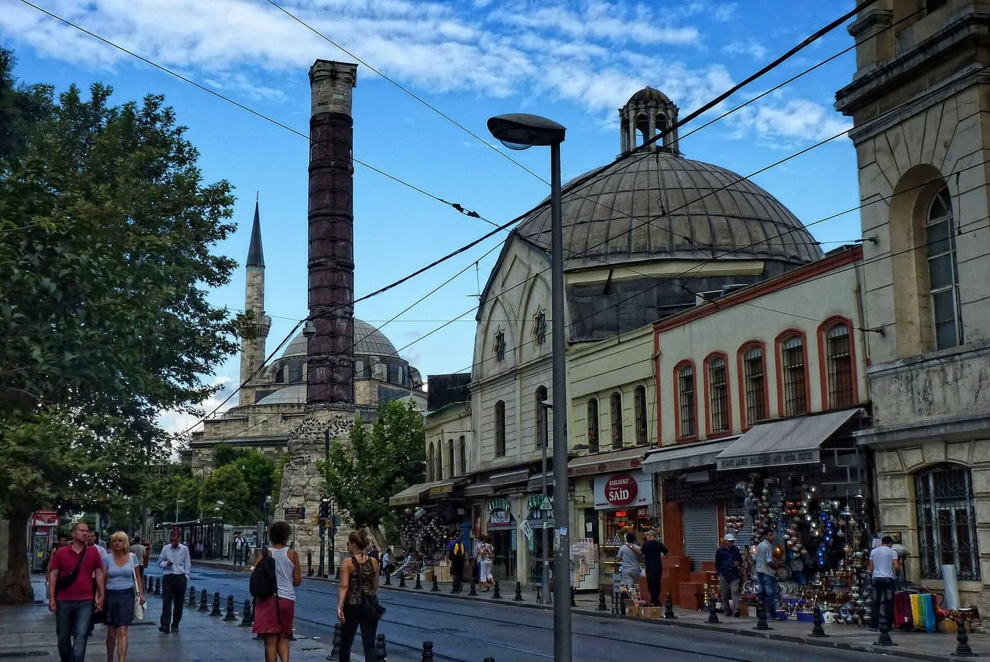 The domed Çemberlitaş Hamamı on Divan Yolu, with the Column of Constantine rising beside it and shoppers on the pavement