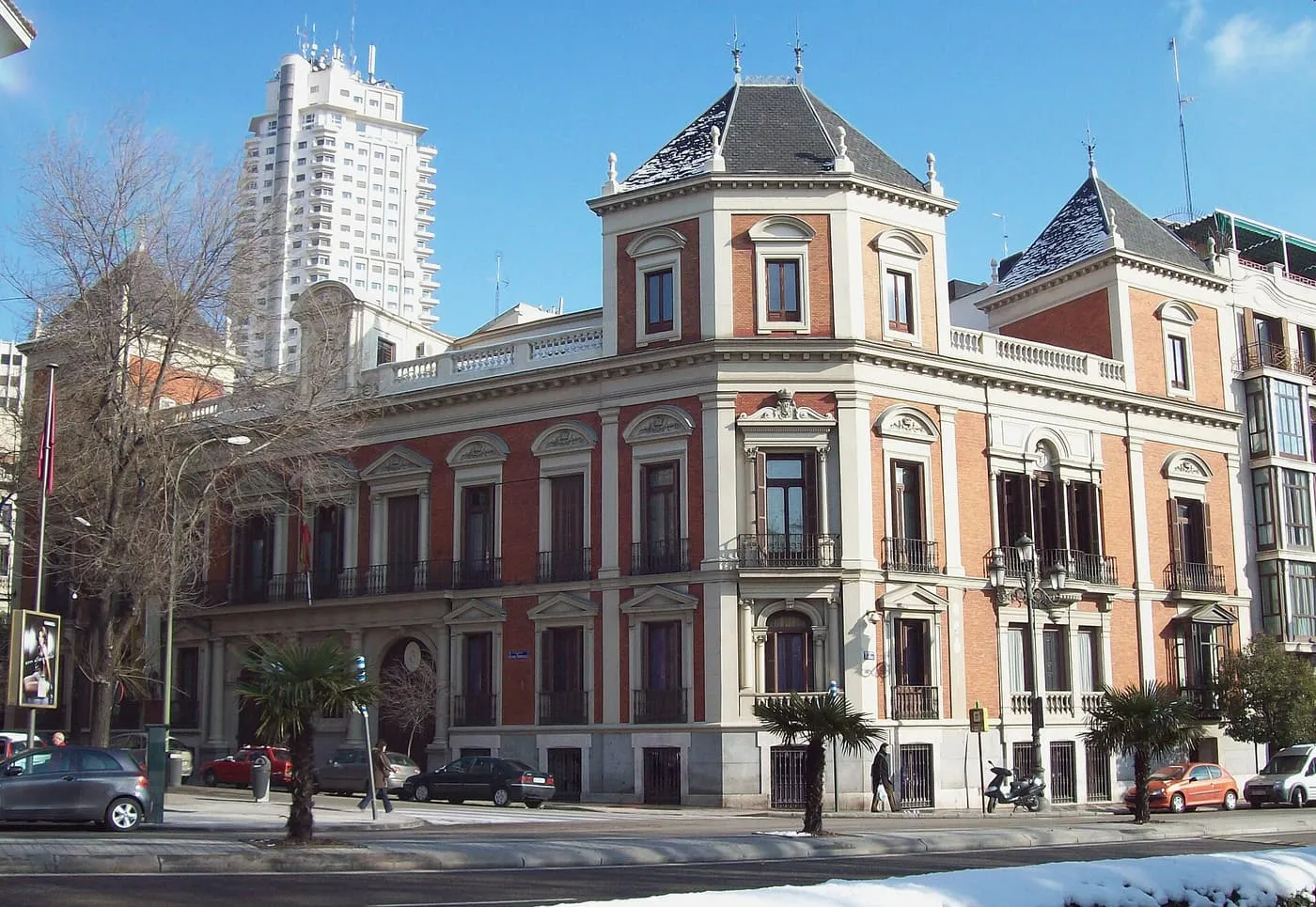 The red-brick and white-stone façade of the Cerralbo Museum on a street corner, with a tall white tower block behind it