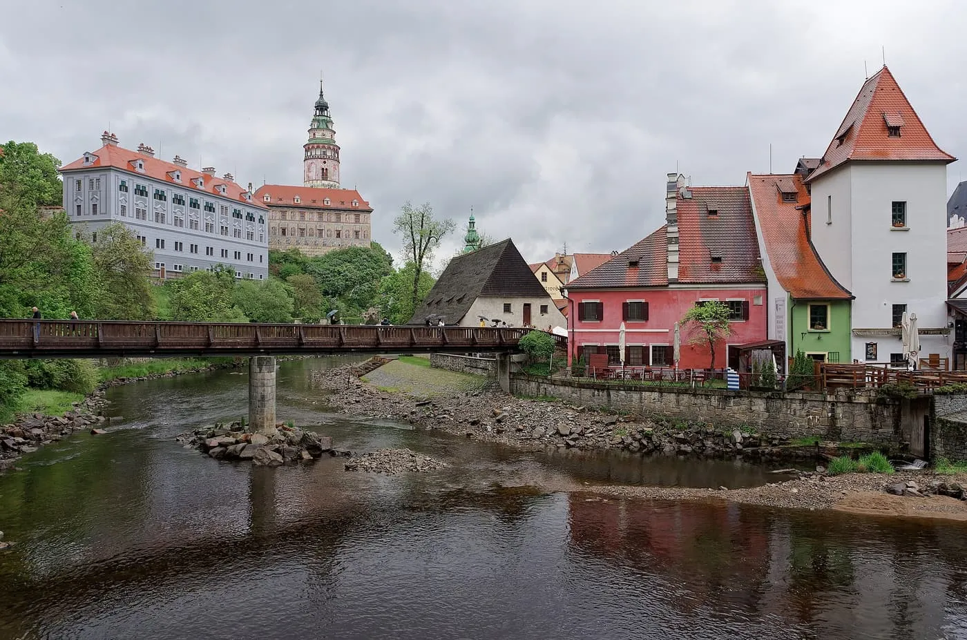 The colourful tower of Český Krumlov Castle above the Vltava river, with red-roofed houses on the bank