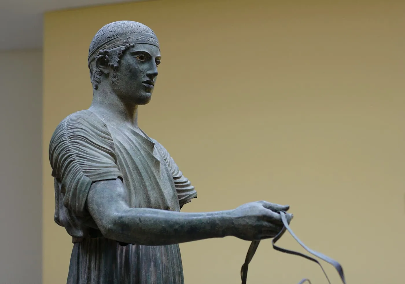 The bronze Charioteer of Delphi in the museum, holding the reins in one outstretched hand