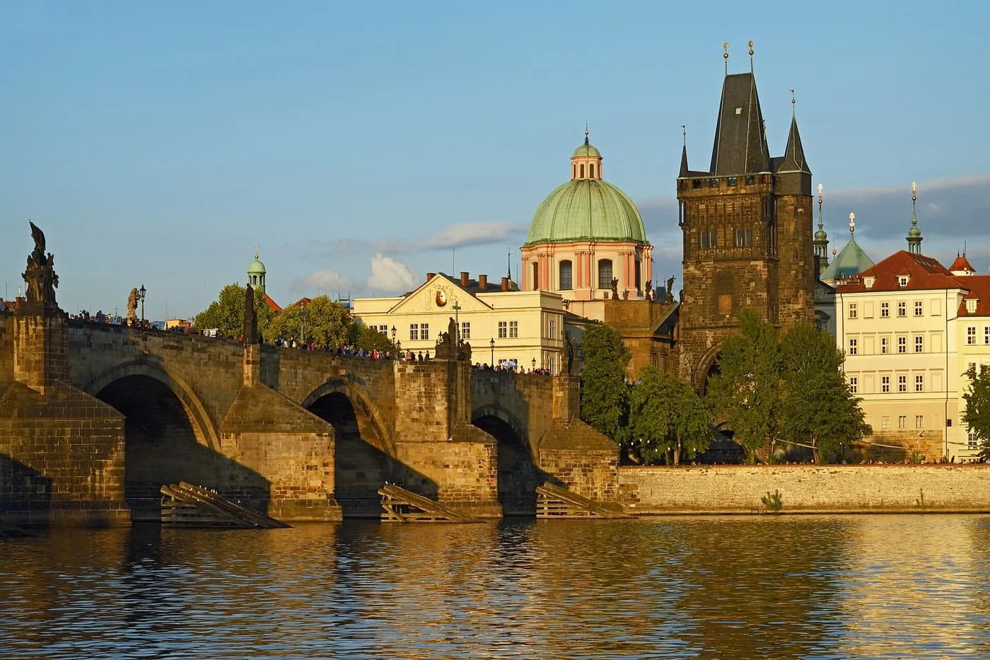 Charles Bridge and the Old Town Bridge Tower from the Vltava, with the green dome of the Church of St Francis of Assisi behind