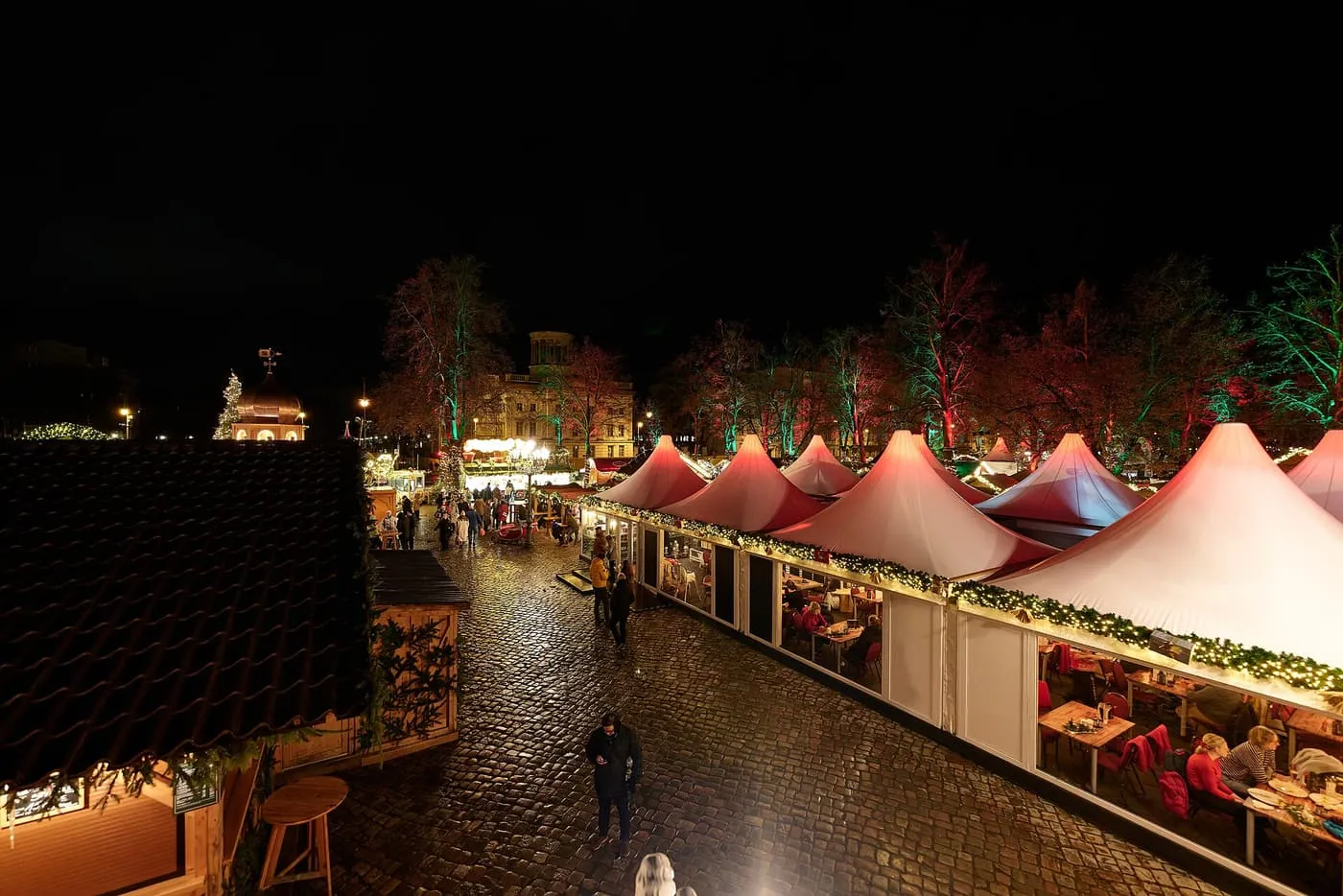 Wooden market huts with lit roofs around the bronze equestrian statue in the forecourt of Charlottenburg Palace at night
