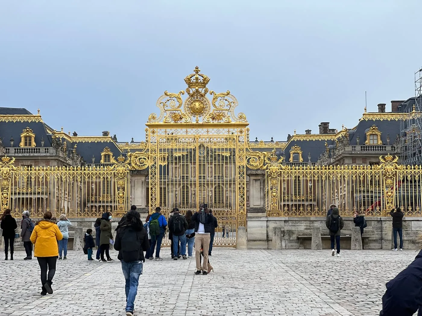 Visitors in the cobbled forecourt in front of the gilded Grille Royale and the Palace of Versailles