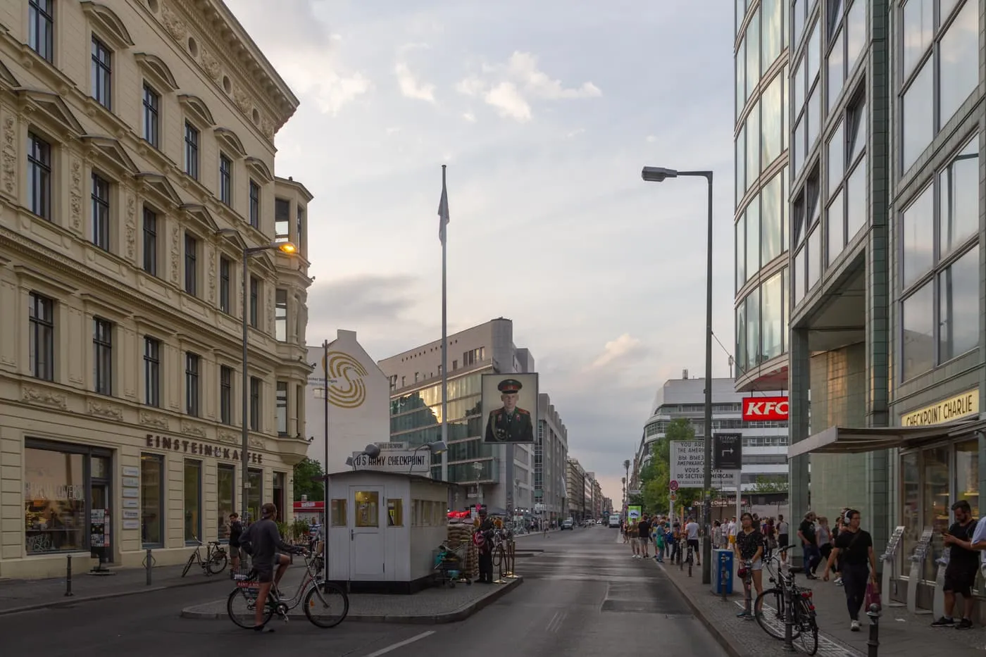 The white US Army checkpoint booth at Checkpoint Charlie on Friedrichstraße, with sandbags, the portrait of a soldier on a pole and the sector sign beyond
