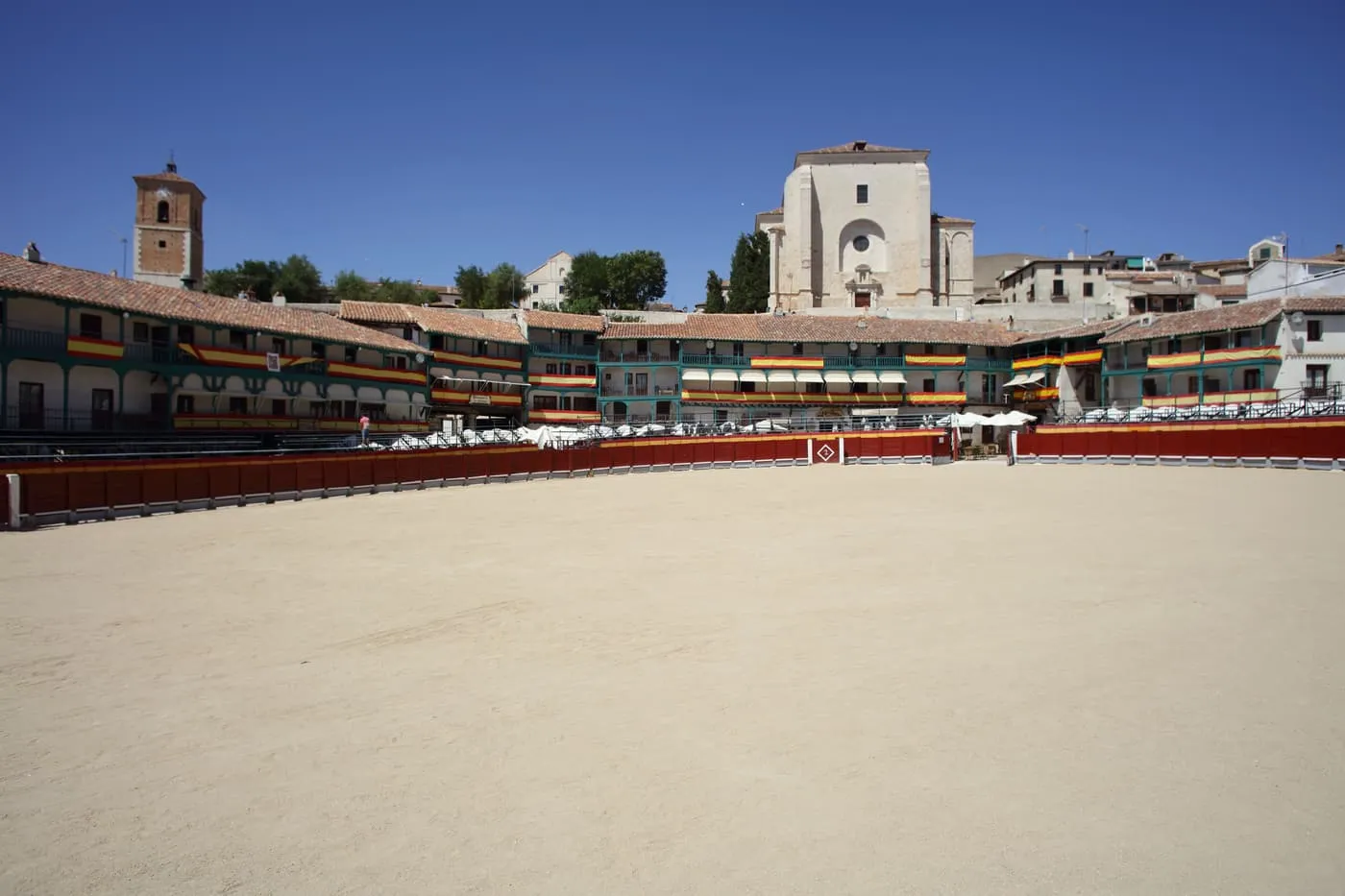 Chinchón's Plaza Mayor with sand laid over the square for a bullfight, ringed by balconied houses and a church behind