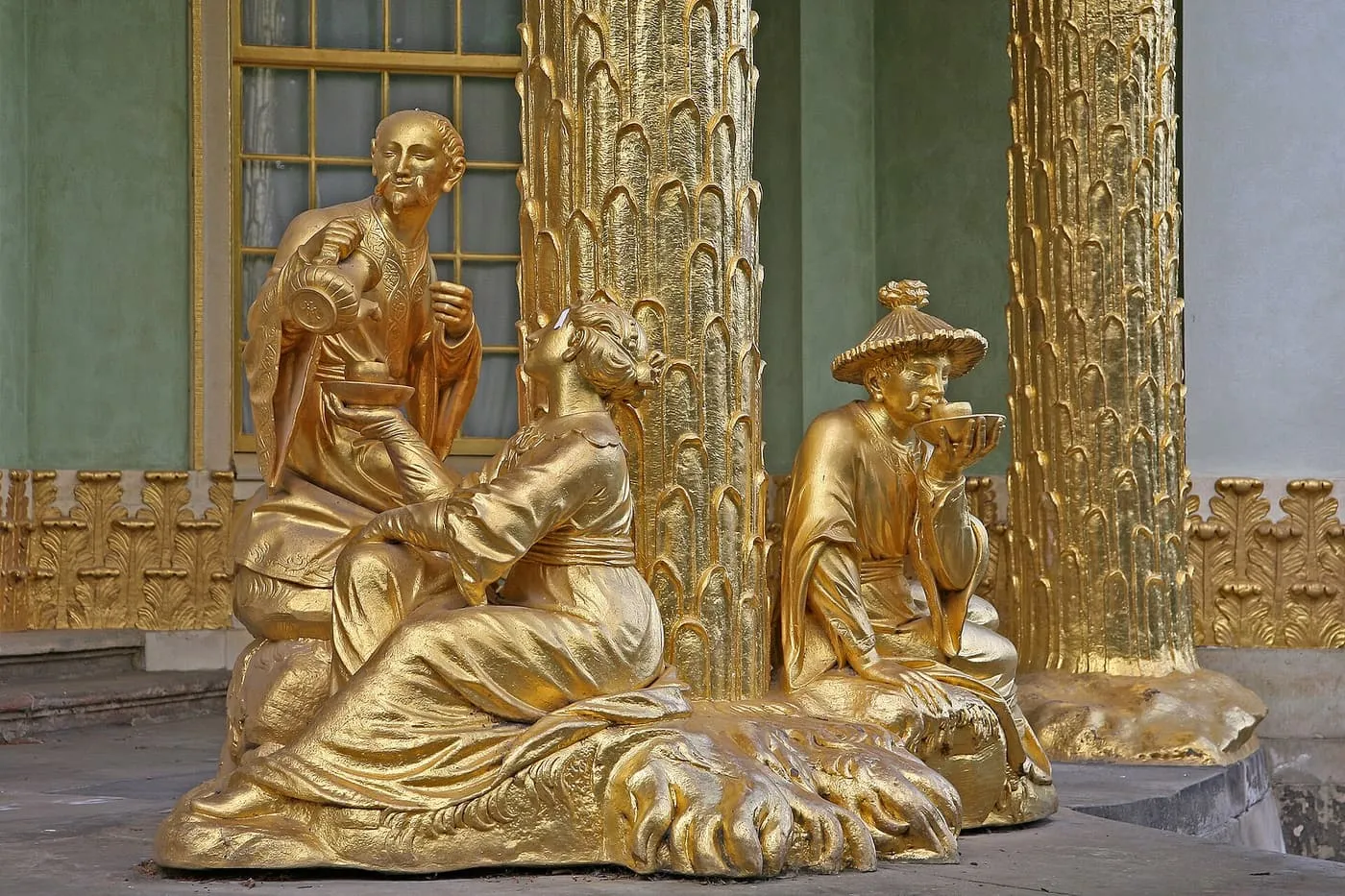 Gilded figures drinking tea beneath the gilded palm-tree columns of the Chinese House