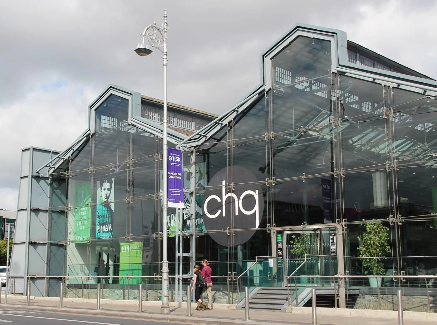 The glass and steel front of the CHQ building on Custom House Quay, with the chq sign and banners behind a street lamp
