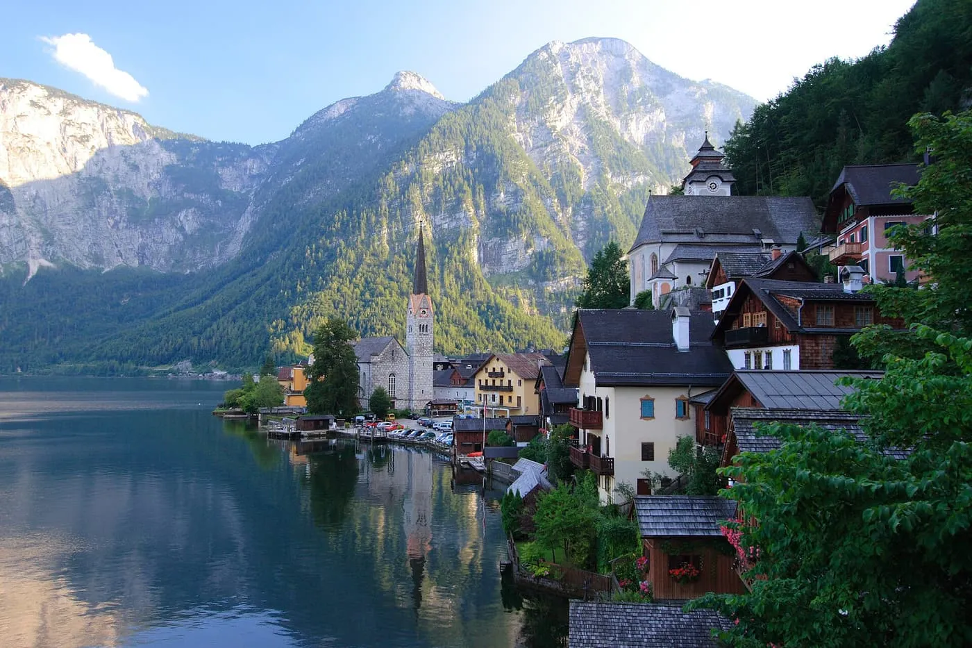 Hallstatt's Protestant church spire and lakeside houses below steep mountains, with the lake on the left
