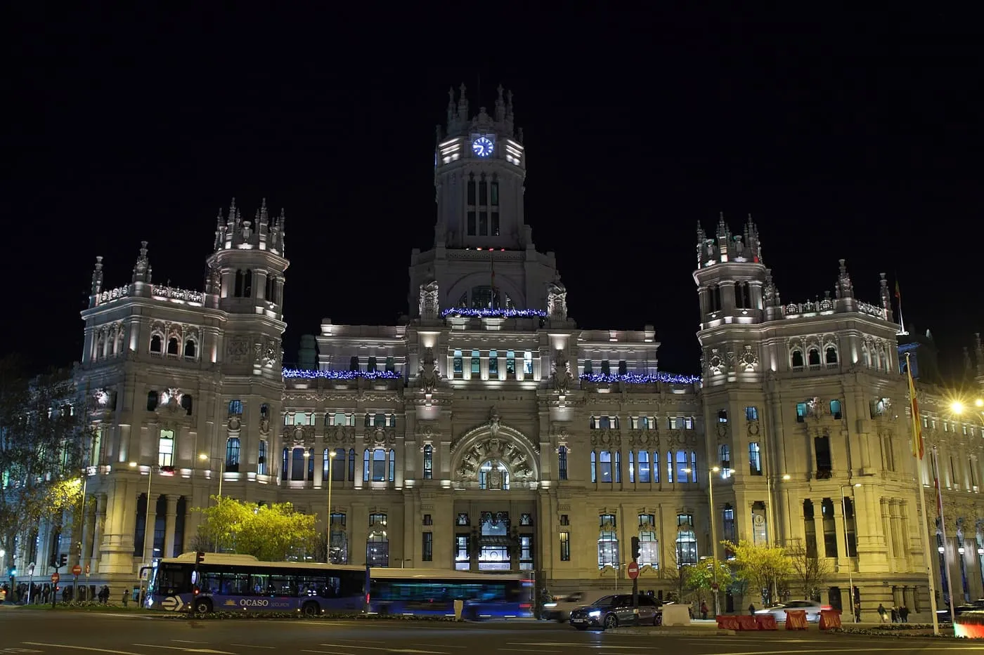 The Palacio de Cibeles lit at night, with strings of blue Christmas lights along its façade