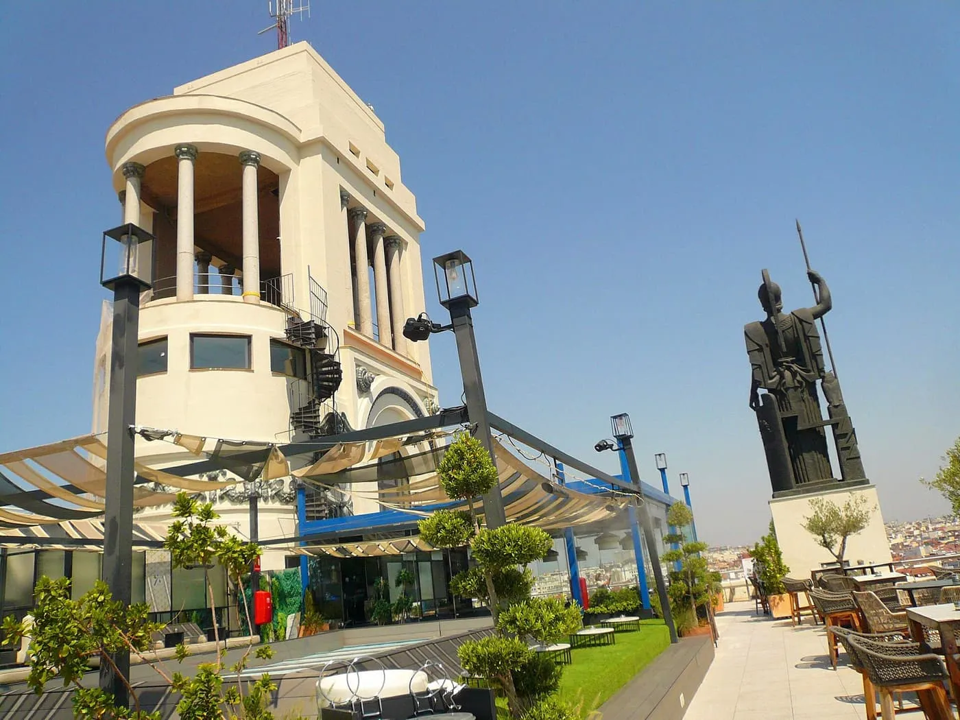 The rooftop terrace of the Círculo de Bellas Artes, with the dark bronze statue of Minerva on a plinth, the tower beside it and tables along the edge