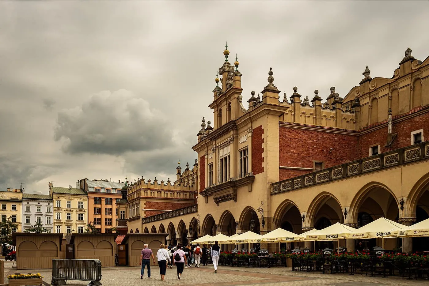 The Cloth Hall's arcades, decorated attic and pinnacles above café umbrellas on the Main Market Square