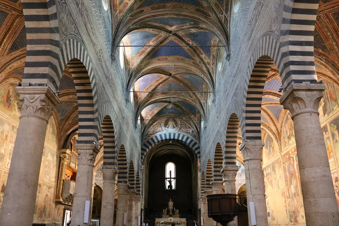 The nave of the Collegiata, with striped arches and frescoed walls
