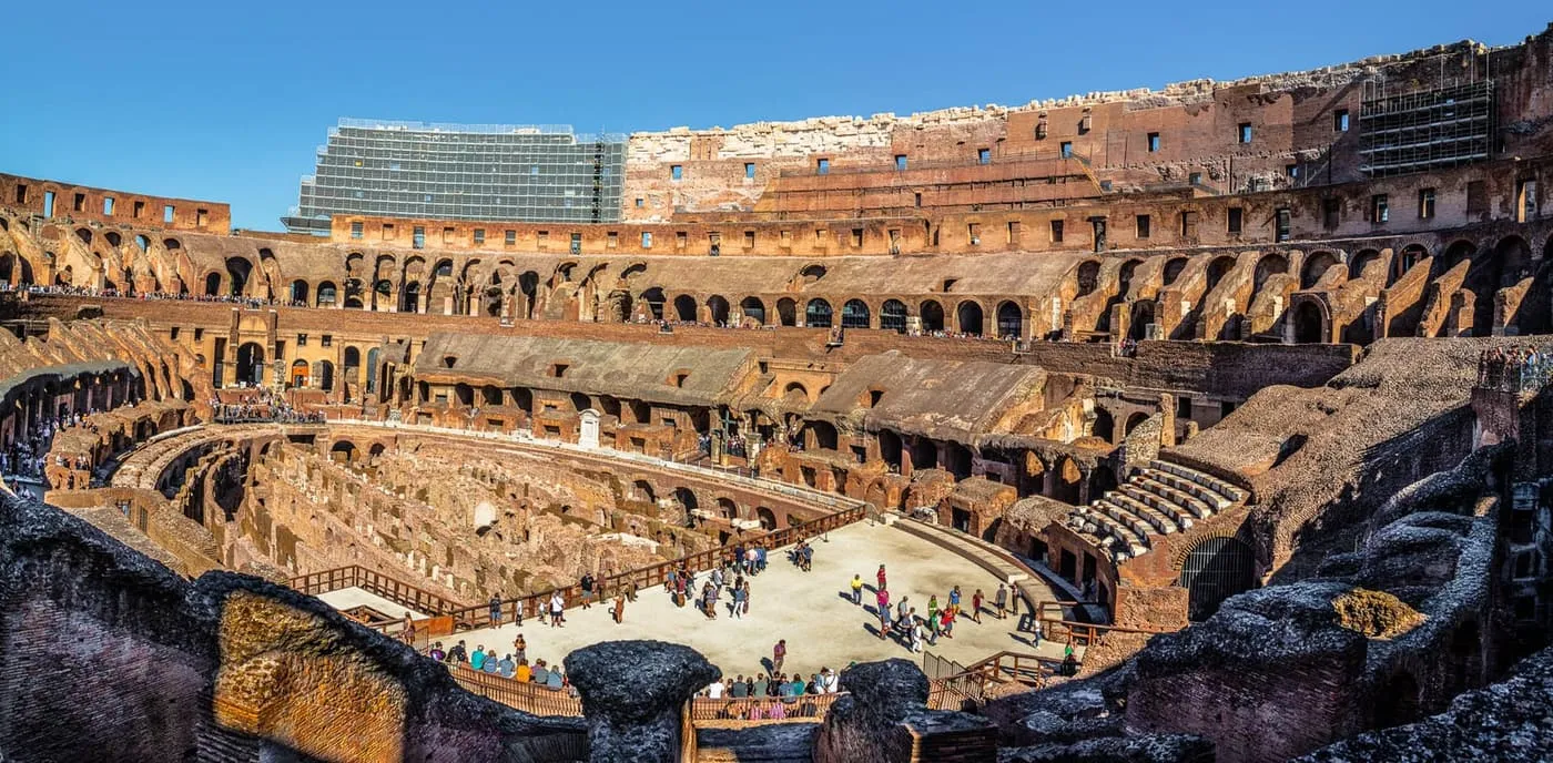 Inside the Colosseum, looking across the reconstructed arena floor to the tiers of seating and the exposed passages beside it